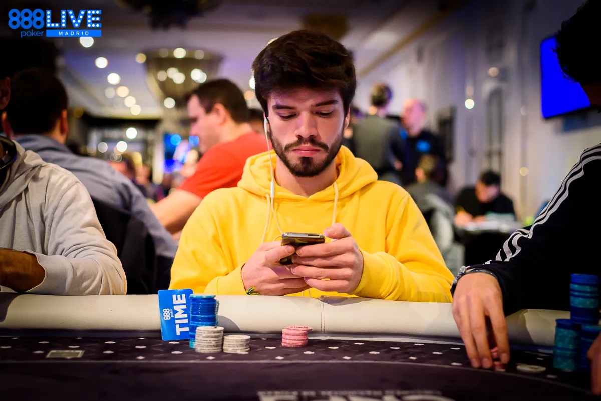 Jogador olha celular na mesa de poker
