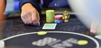 Mesa de poker com fichas e a mão de um jogador