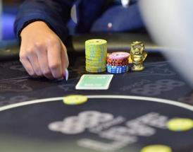 Mesa de poker com fichas e a mão de um jogador