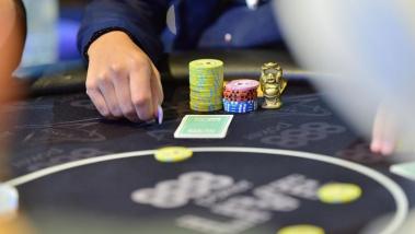 Mesa de poker com fichas e a mão de um jogador
